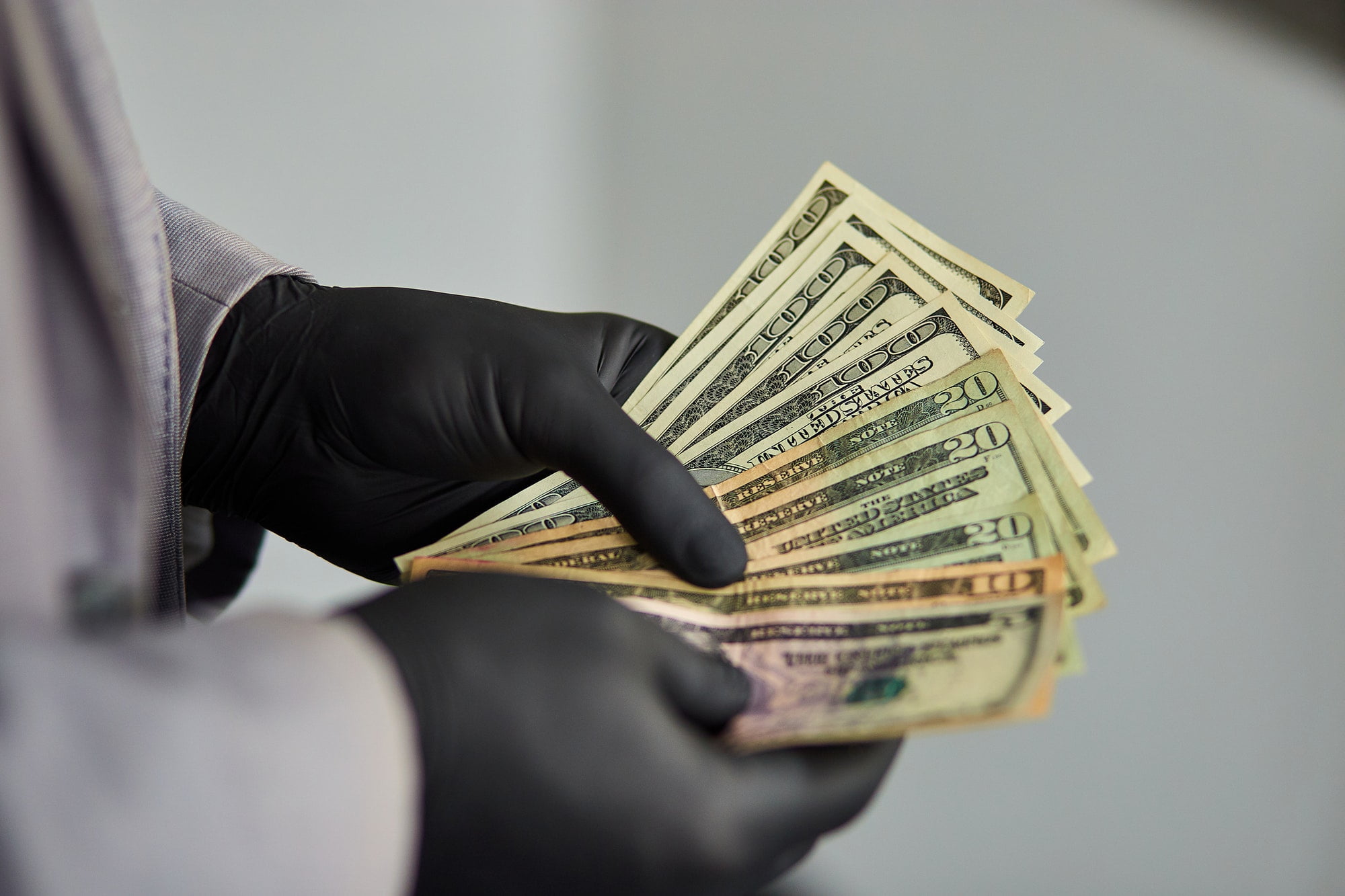 Man holding money dollars in hand in black medical gloves.