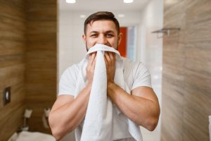 Man wipes his face with a towel, morning hygiene