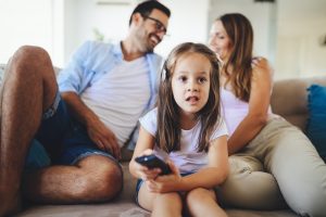 Young girl watching tv with her parents