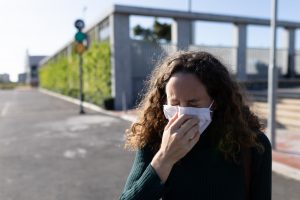 Caucasian woman wearing a protective mask and coughing out in the streets