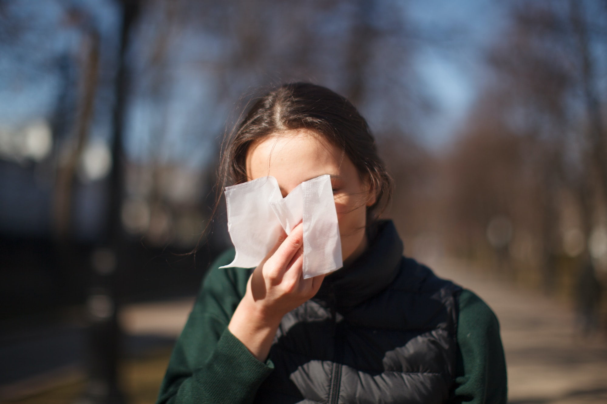 female outdoor sneeze and cover her face with napkin