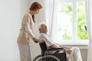 Smiling nurse supporting disabled senior man in the wheelchair