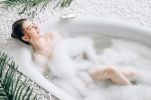 Attractive lady lying in bath with foam, top view