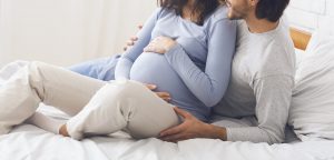 Pregnant couple relaxing on bed at home