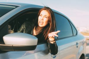 Beautiful brunette long hair angry young asian woman driving and screaming in car