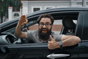 Charismatic man holding car keys showing thumbs up