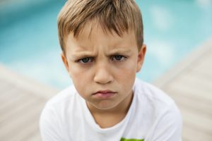 Portrait of angry boy against swimming pool