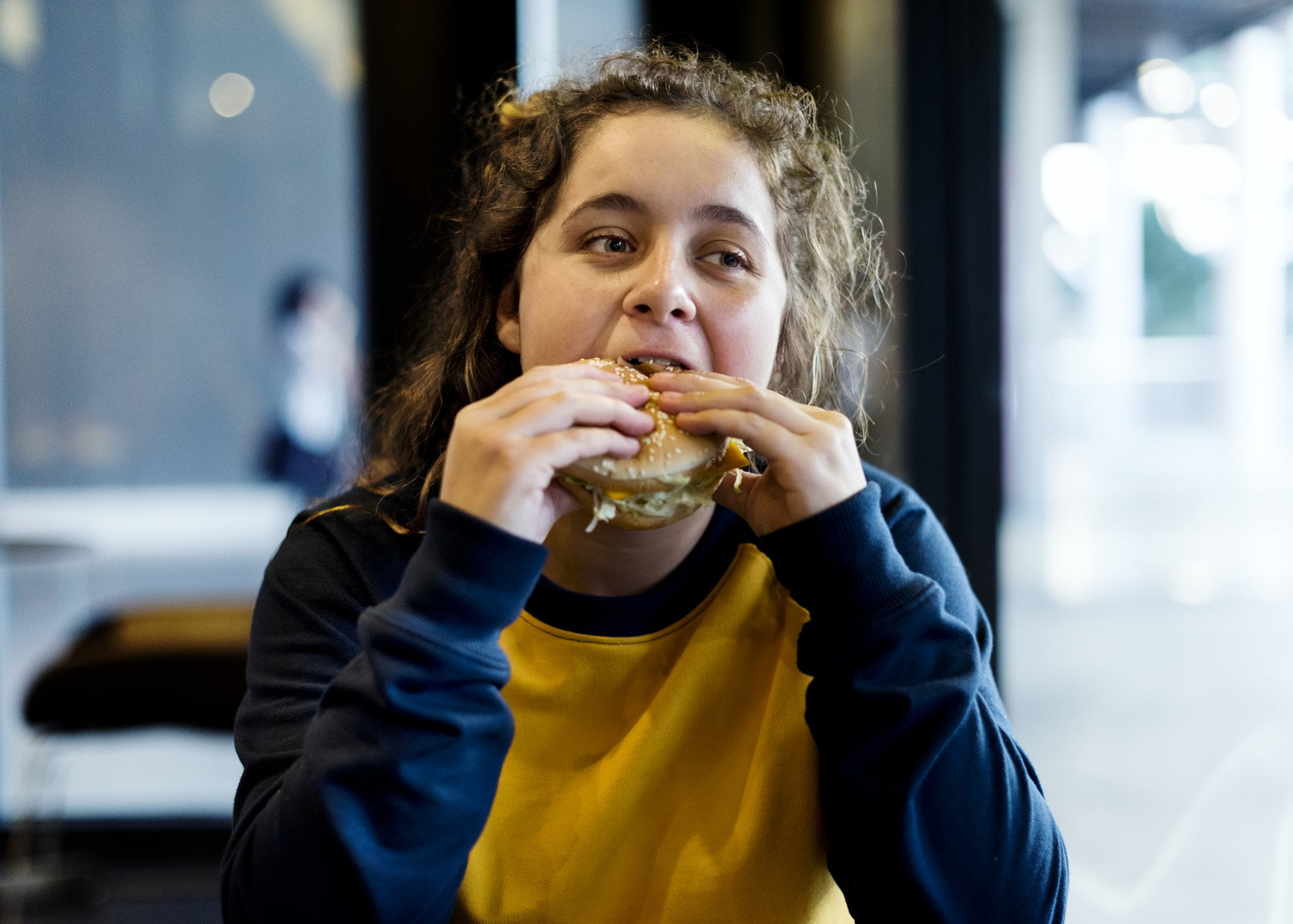 Close up of teenage girl eating hamburger obesity concept