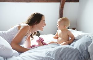 Mother and baby playing on bed