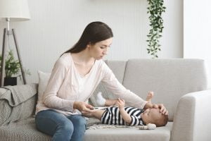 Concerned mother checking temperature of her sick newborn child