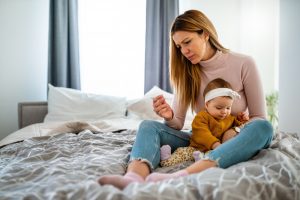 Mother measuring temperature of her ill kid. Sick child with high fever, mother holding thermometer